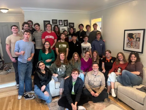 A large FRAT college group gathered together in a living room.