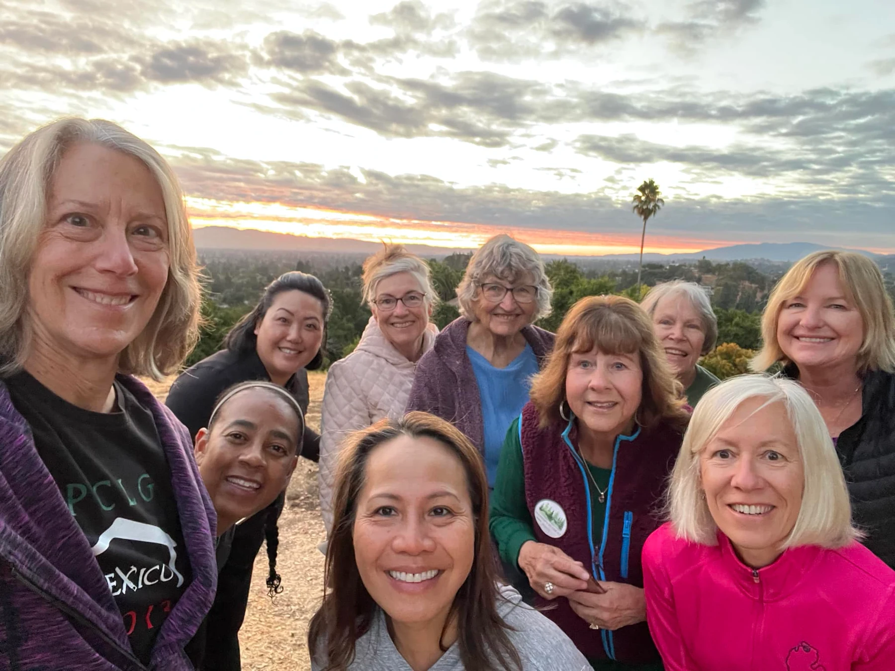 Members of our fellowship together outdoors, the valley behind them at sunset.