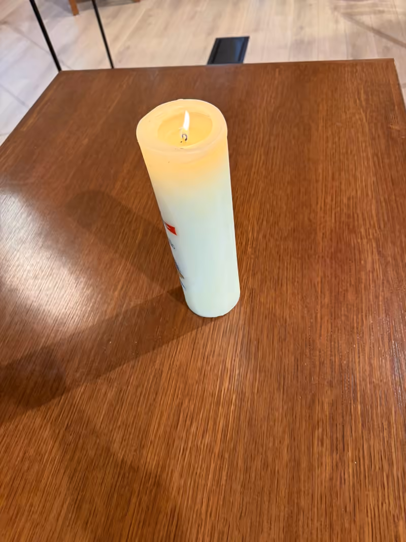 A candle burning on a wooden table in the PCLG Sanctuary.