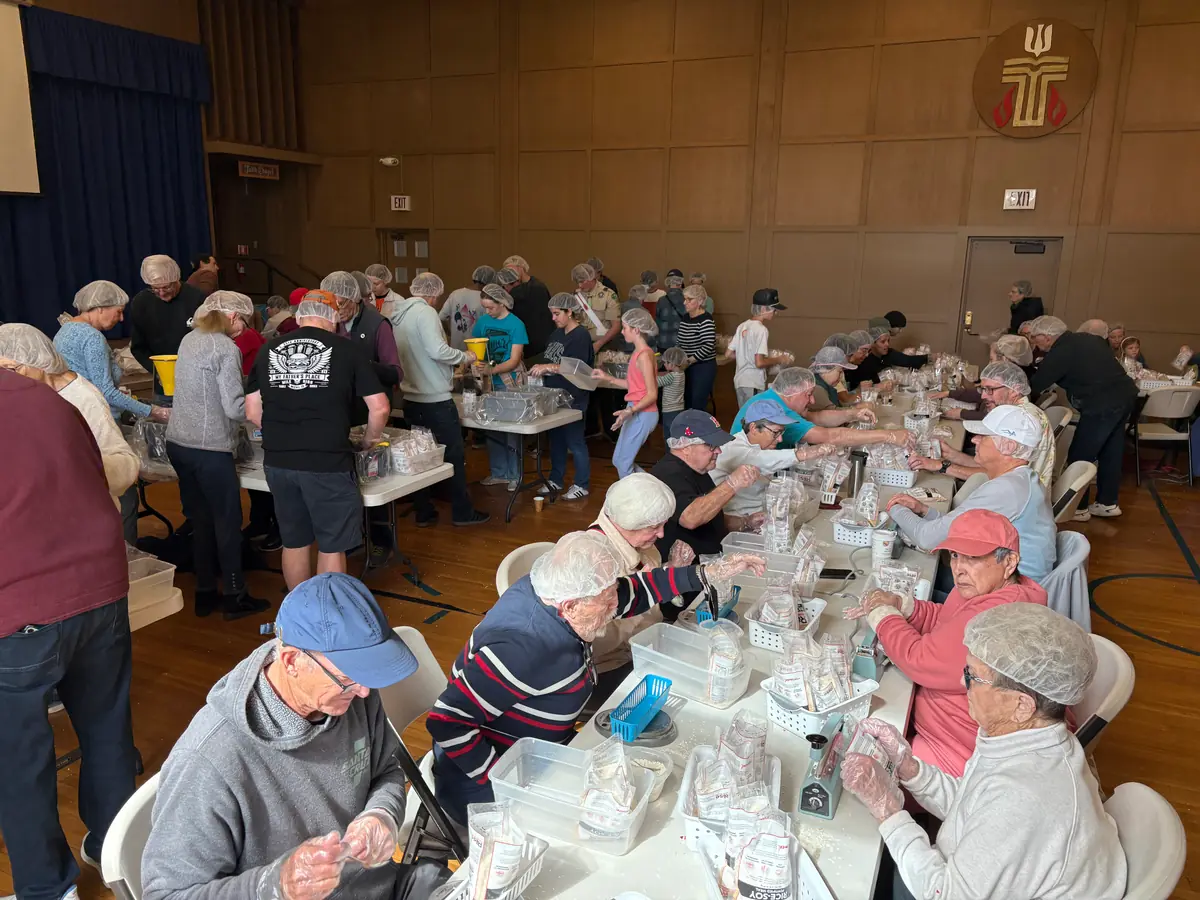 PCLG volunteers filling meal bags together at a Rise Against Hunger packing station.